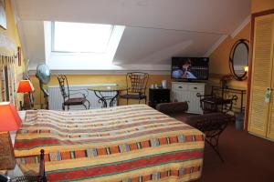 Hotel Le Relais de Pommard في فرانكورشومب: غرفة نوم بسرير وتلفزيون بشاشة مسطحة