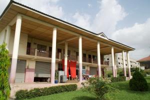 a large building with white columns at Sign of Silence Hostel in Kumasi