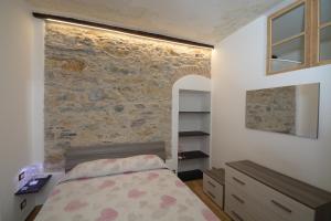 1 dormitorio con cama y pared de piedra en VICO DURAZZO APARTMENT, en Génova