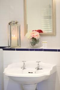 a bathroom sink with a mirror and a vase of flowers at The Bunk Inn in Newbury