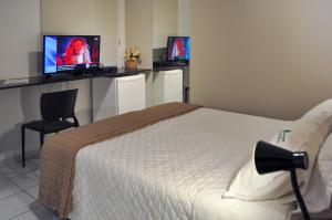 um quarto com uma cama e dois monitores numa parede em Suites Residence em Recife