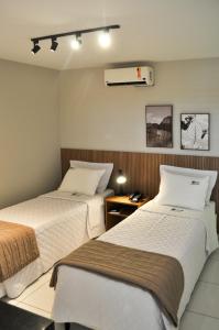 um quarto de hotel com duas camas e ar condicionado em Suites Residence em Recife
