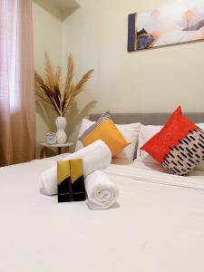 a white bed with colorful pillows on it at Luxury Suites at Brenthill Baguio City in Baguio