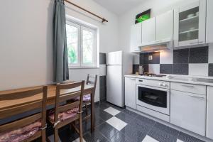 - une cuisine avec des appareils blancs, une table et des chaises dans l'établissement Apartmani Ivušić, à Dubrava