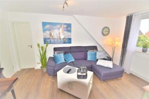 uma sala de estar com um sofá roxo e almofadas azuis em Schatzinsel em Büsum