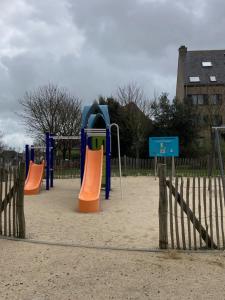 a playground with orange and blue play equipment in the sand at Strandstudio in hartje Koksijde in Koksijde