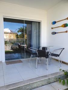 a patio with chairs and a table and glass doors at Casa Duplex Aconchegante de Frente para o Mar in Porto Seguro
