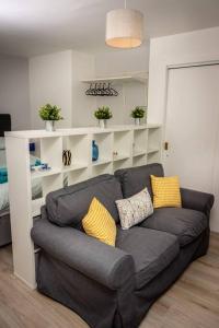 a living room with a gray couch with yellow pillows at Modern bright studio apartment in south Glasgow in Glasgow