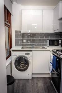 uma cozinha com uma máquina de lavar roupa e um lavatório em Modern bright studio apartment in south Glasgow em Glasgow