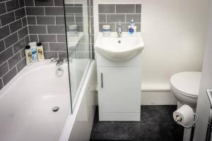 Baño blanco con lavabo y aseo en Modern bright studio apartment in south Glasgow, en Glasgow