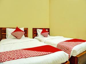 2 camas en una habitación con sábanas rojas y blancas en OYO 92386 Homestay Juwita Perdana Syariah, 