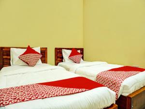 two beds in a room with red and white sheets at OYO 92386 Homestay Juwita Perdana Syariah 