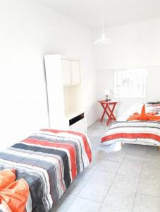 ブエノスアイレスにあるPiran Loftの白いベッドルーム(ベッド2台、テーブル付)