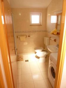 a bathroom with a toilet and a sink and a washing machine at Apartments Boris in Vodice