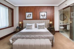 Vogue Hotel Supreme Istanbul في إسطنبول: غرفة نوم بسرير كبير ومرآة