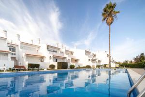 a villa with a palm tree and a swimming pool at Oura Parque Apartamentos Turisticos in Albufeira