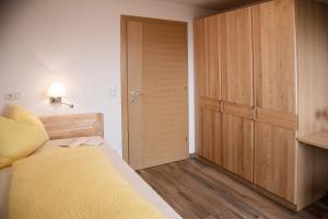 1 dormitorio con cama y armario de madera en Forchnerhof Apt Ploseblick, en Maranza