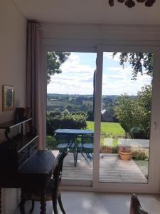 a sliding glass door leading to a patio with a table at Sous la charmille. in Cerisy-la-Salle