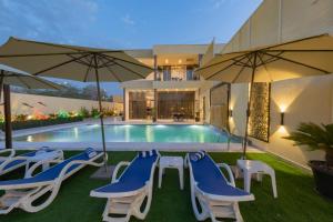 a pool with blue and white chairs and umbrellas at Adam's Luxury Villa DeadSea in Sowayma