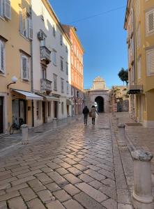 two people walking down a cobblestone street at Emar Apartment - old town center in Zadar