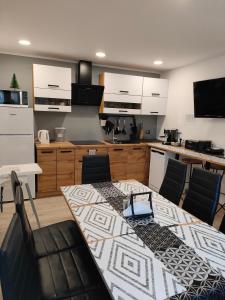 a kitchen with a table and chairs and a kitchen with white cabinets at Apartament przy Wyciągu z jacuzzi in Bukowina Tatrzańska