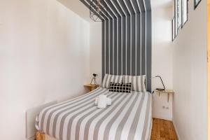 1 dormitorio con 1 cama con colcha a rayas en Class and cozy desing tram, en Saint-Étienne