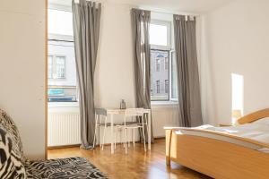 a bedroom with a bed and a table and windows at comfortable 3BR -Belvedere -Perfect for long stays in Vienna