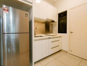 a kitchen with a stainless steel refrigerator and white cabinets at Meridin Medini, Iskandar Puteri, Johor in Nusajaya