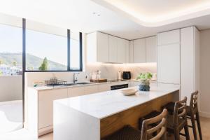 a kitchen with white cabinets and a large window at The View - Brand new Penthouse with private rooftop pool in Cape Town