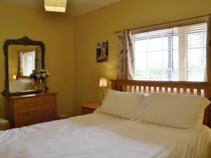 1 dormitorio con cama blanca y espejo en High Moor Cottage, en Dufton