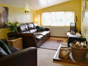 a living room with a leather couch and a television at High Moor Cottage in Dufton