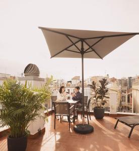 Dos personas sentadas en una mesa en un balcón con sombrilla en Anderson City Flats, en Valencia