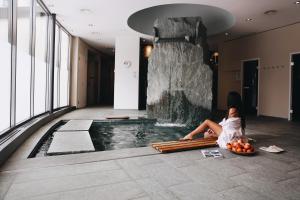uma mulher sentada no chão ao lado de uma piscina em Hotel Steinbock Pontresina em Pontresina