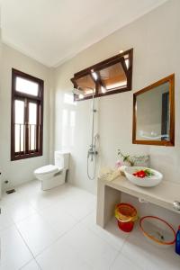 La salle de bains est pourvue d'un lavabo, de toilettes et d'un miroir. dans l'établissement Pink Beach Homestay, à Hội An