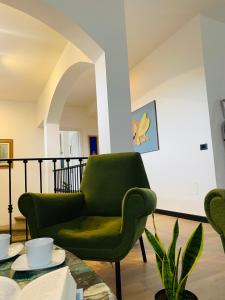 una sala de estar con una silla verde y una mesa en ArtGallery Apartment - Villa immersa nel verde - Deluxe, en Viterbo