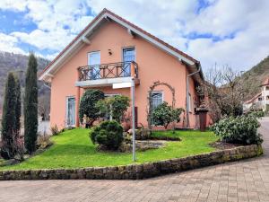 een roze huis met een balkon bij Ferienwohnung An der Korkeiche in Rinnthal