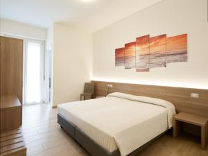 sypialnia z łóżkiem i dwoma obrazami na ścianie w obiekcie HOTELRISTORANTE IL PUNTO w mieście Marotta