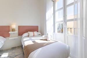 ein weißes Schlafzimmer mit einem Bett und einem Fenster in der Unterkunft Muro city center suite by Valcambre in Sevilla