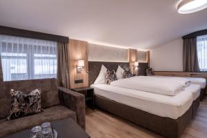 Habitación de hotel con cama grande y sofá en Alphotel Garni Salner en Ischgl