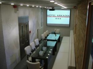 a conference room with a table and chairs and a screen at Hotel Arkadia in Pécs