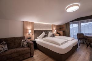 a bedroom with a large bed and a couch at Alphotel Garni Salner in Ischgl
