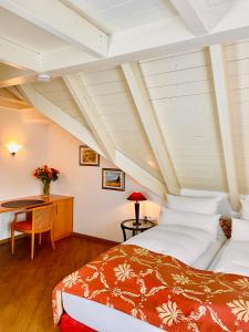 a bedroom with two beds and a desk in a attic at Hotel Im Winkel Appartements und Zimmer in Langenargen