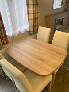 un tavolo e sedie in legno in una stanza con camino di 173A Woodland Way a Porthmadog