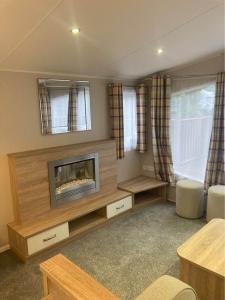 uma sala de estar com uma lareira e uma mesa em 173A Woodland Way em Porthmadog