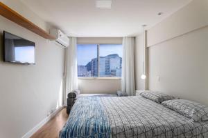 um quarto com uma cama e uma grande janela em Flat em Copacabana no Rio de Janeiro