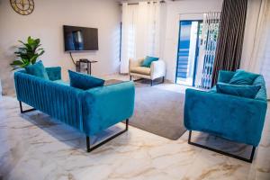 een woonkamer met twee blauwe stoelen en een televisie bij Blue Agave F1 in Lusaka