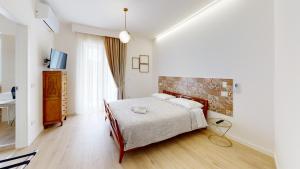 a white bedroom with a bed and a television at Accòmodati B&B in Marina di Gioiosa Ionica
