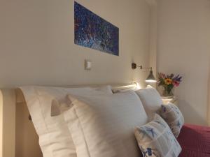 a bed with white pillows and a painting on the wall at Aristea Studios in Sarti