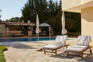 two chairs and umbrellas sitting next to a pool at Flyin' High Luxury Suite in Metókhi