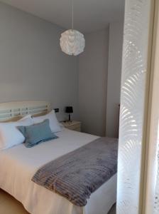 1 dormitorio con cama blanca y lámpara colgante en APARTAMENTOS TURISTICOS LAS CINCO JOYAS, en Linares